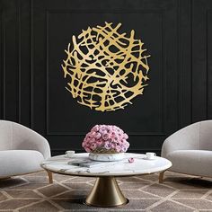 a living room with two chairs and a table in front of a wall that has gold paint on it