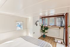 a bedroom with white walls and wooden floors, has a large bed in the corner