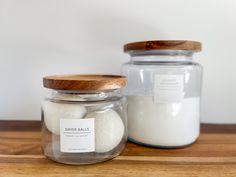 two jars filled with white sand on top of a wooden table