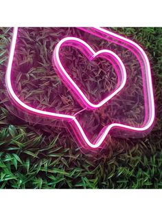 a neon sign that is sitting in the grass with a heart on it's side