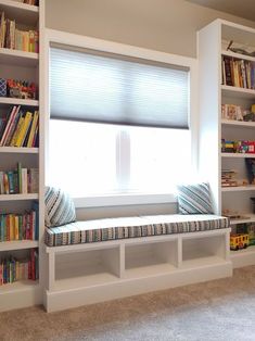 a window seat in front of a book shelf filled with books