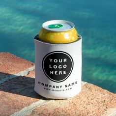 a beer can sitting on top of a rock near the water