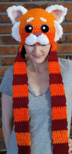 a woman wearing an orange and red knitted animal hat