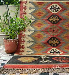 an old rug is on the ground next to a potted plant