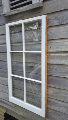 an old window on the side of a house with wood siding and white glass panes