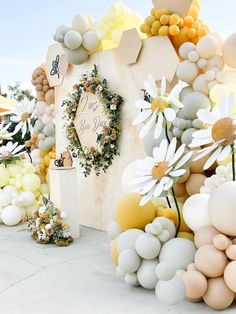 a bunch of balloons that are on the ground and in front of a wall with flowers