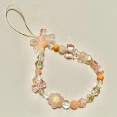 a bracelet with flowers and pearls on it is hanging from a cord that has a bow