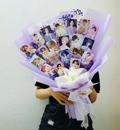 a woman holding a bunch of photos with flowers in her hands and purple ribbons around her neck