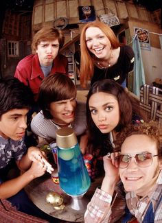 a group of young people posing for a photo in front of an old fashioned camera