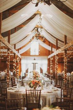 the inside of a barn with tables and chairs set up for a formal dinner or function