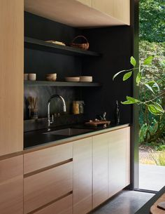 a kitchen with wooden cabinets and black counter tops next to a sliding glass door that leads outside