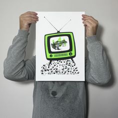 a person holding up a card with an old tv on it in front of their face