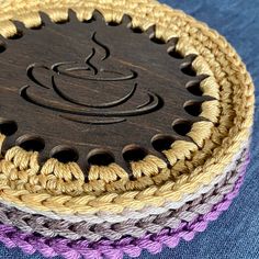 a close up of a wooden object with yarn on it's sides and a coffee cup in the middle