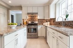 a kitchen with white cabinets and granite counter tops, stainless steel appliances and dishwasher