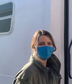 a woman wearing a blue face mask standing in front of a white trailer with the door open