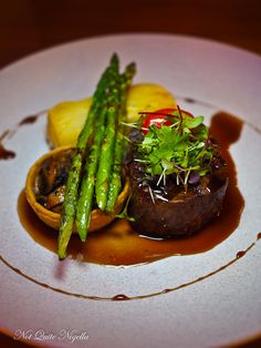 a white plate topped with meat and asparagus