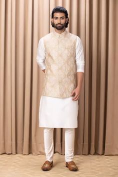 Beige sleeveless nehru jacket with floral pattern thread work embroidery. Comes with an ivory white kurta and ivory churidar.
Component: 3
Pattern: Embroidered
Type Of Work: Floral Patterns
Neckline: Mandarin Collar
Sleeve Type: Bundi: Sleeveless, Kurta: Full Sleeves
Fabric: Cotton and Silk, Lining: Twill Satin
Color: Beige
Other Details: 
Floral pattern work on bundi
Note: Pant worn by the model is not for sale
Occasion: Wedding - Aza Fashions Satin Kurta, Nehru Jacket For Men, Kurta Set For Men, White Kurta, Nehru Jacket, Couture Outfits, Nehru Jackets, Mens Luxury Fashion, Satin Color