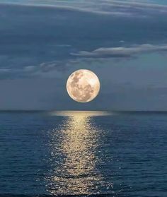 the full moon shines brightly in the sky above the ocean water as it reflects on the surface of the water