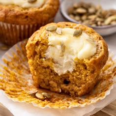 two muffins with white frosting and pumpkin seeds