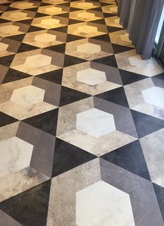 a black and white checkered floor with some curtains in the backround, next to a window