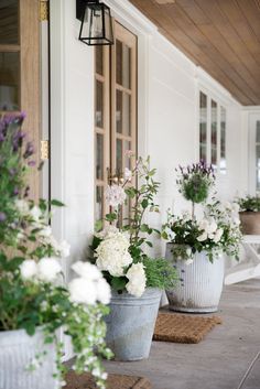 three buckets filled with flowers sitting on the front porch