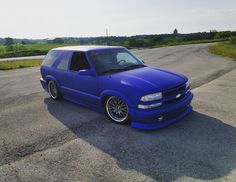 a blue car is parked on the side of the road in front of some grass