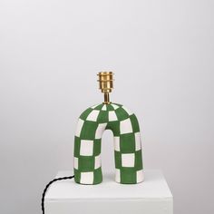 a green and white checkered lamp sitting on top of a white blocky surface