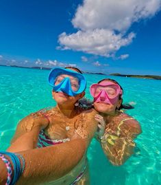 two people wearing snorkels in the water with their faces close to each other