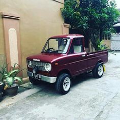 a red truck parked in front of a building with potted plants on the side