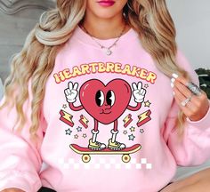 Retro Heartbreaker (2) Sweatshirt | Unisex Comfortable Pullover for Cool Weather | Unique Gifts for Family Friends   Indulge in the spirit of love and fashion with our exclusive Happy Valentine's Day crewnecks! Curated with passion and crafted for comfort, these crewnecks blend heartfelt designs with premium quality, ensuring you celebrate in style. Embrace the essence of romance and joy with each piece, perfect for cozy gatherings or expressing your affection in a chic, casual style.    Key Features: High-Quality Material: Made from soft and durable fabric, this sweatshirt is built to last and keep you warm throughout the season. Unisex Design: This versatile pullover suits all genders, offering a relaxed and comfortable fit. Charming Appeal: Our cute fall sweatshirt is designed to add a Pink Long Sleeve T-shirt With Heart Graphic, Trendy Heart Graphic Sweatshirt For Winter, Trendy Winter Sweatshirt With Heart Graphic, Trendy Long Sleeve Sweatshirt With Heart Print, Oversized Long Sleeve Top With Heart Graphic, Pink Casual Sweatshirt With Heart Graphic, Casual Pink Sweatshirt With Heart Graphic, Pink Long Sleeve Top With Heart Graphic, Cute Sweatshirt With Heart Graphic And Crew Neck