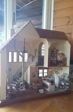 a doll house is sitting on the floor in front of a window with lots of windows