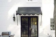 the front door of a white house with black awnings on it's side