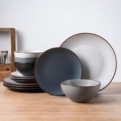 a stack of plates and bowls sitting on top of a wooden table