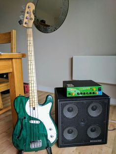 a green guitar sitting next to an amp