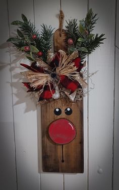 a wooden reindeer head hanging on the wall with pine branches and berries in it's mouth