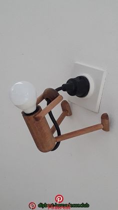 a wooden object with a light on it's side hanging from the ceiling in front of a white wall