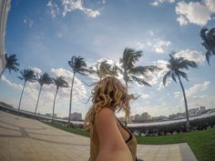 a woman riding a skateboard down a sidewalk next to palm trees and the ocean