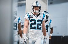 two football players are walking together in the locker room, one is wearing a number 22 jersey