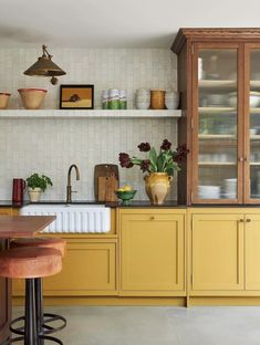 a kitchen with yellow cabinets and wooden stools