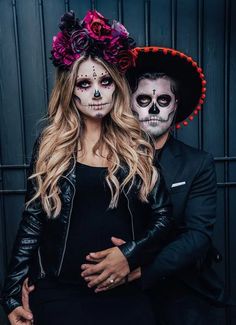 a man and woman in day of the dead makeup pose for a photo with flowers on their head