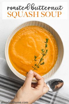 a bowl of roasted butternut squash soup with a hand reaching for the soup in it