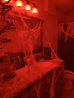 a bathroom decorated for halloween with spider webs hanging from the ceiling and lights on