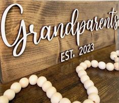 a wooden sign that says grandparents est 2013 and beads are on the table next to it