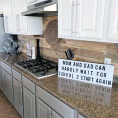 a sign that is sitting on top of a stove in a kitchen with white cabinets