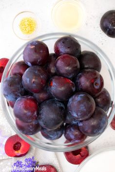 a glass bowl filled with plums next to other ingredients