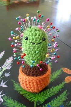 a crocheted cactus with colorful pins on it's head