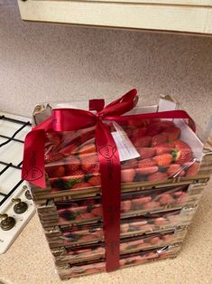 a bunch of strawberries wrapped in plastic and tied with a red ribbon sitting on top of a stove