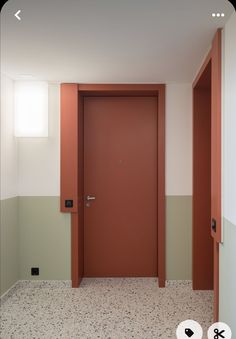 an empty room with a red door and two white doors on either side of it