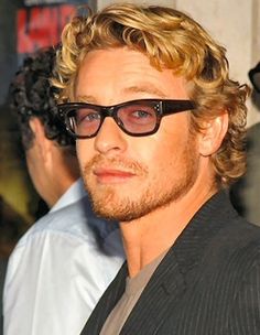 a man with curly hair and glasses at an event