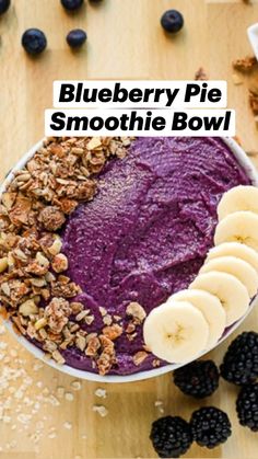 a bowl filled with blueberries and granola next to sliced bananas on a wooden table